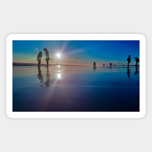 Silhouetted people in a row on a sand beach. Sticker